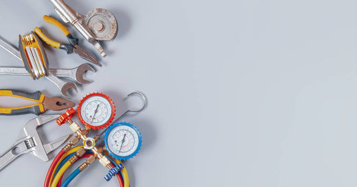 Several tools commonly used in air conditioning system repair and maintenance lined together on a neutral background.