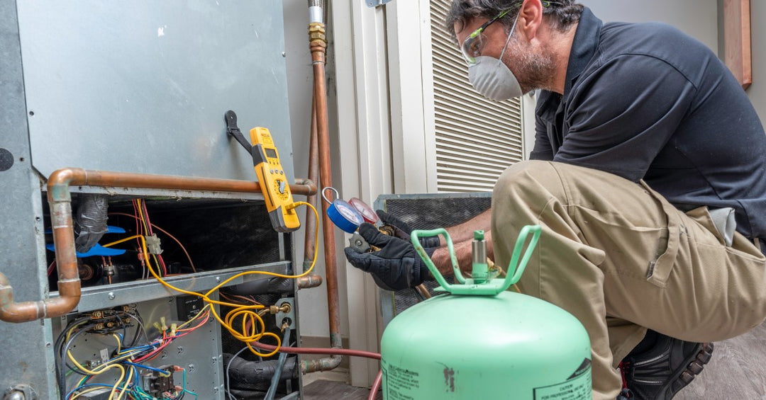 A masked ad gloved technician is working on a heating, ventilation, and air conditioning system and replacing refrigerant.